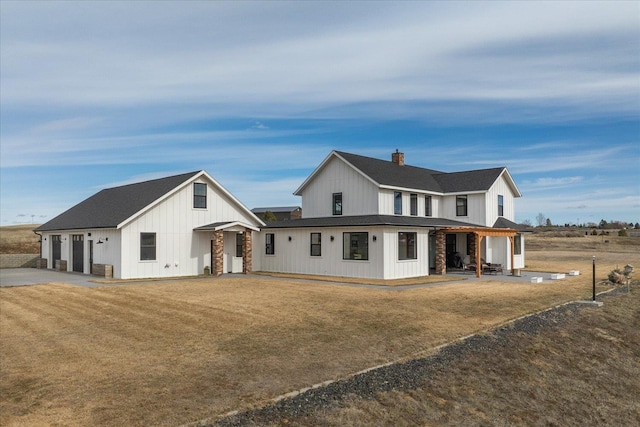 view of front of house featuring a front yard, a garage, board and batten siding, and driveway