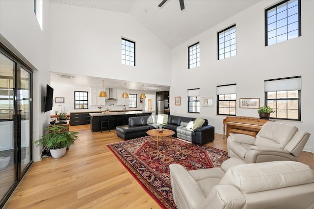 living room featuring visible vents, light wood-style floors, and ceiling fan