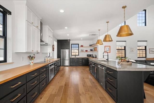 kitchen featuring light wood finished floors, a sink, stainless steel appliances, white cabinetry, and open shelves