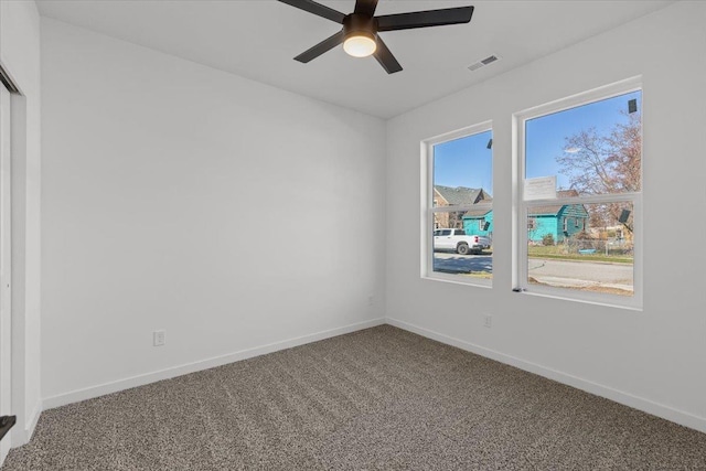 carpeted spare room with visible vents, baseboards, and ceiling fan