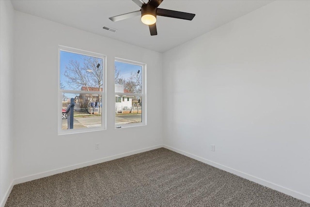 carpeted spare room featuring visible vents, baseboards, and a ceiling fan