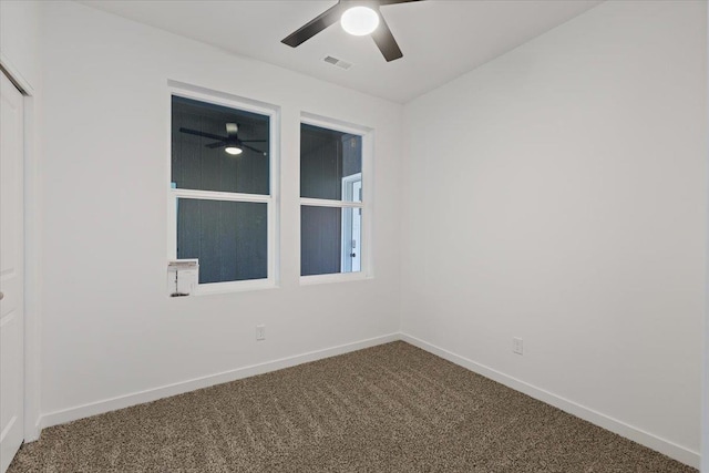 carpeted spare room featuring visible vents, a ceiling fan, and baseboards