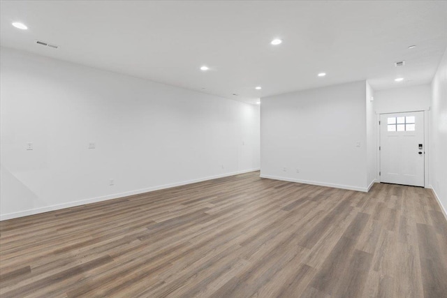 empty room with visible vents, recessed lighting, baseboards, and wood finished floors