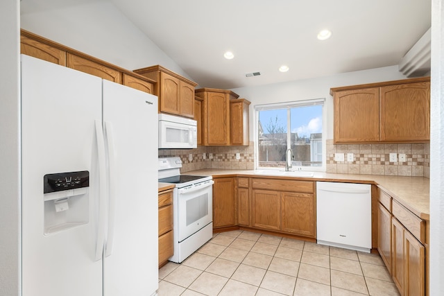 kitchen featuring visible vents, light countertops, decorative backsplash, white appliances, and a sink