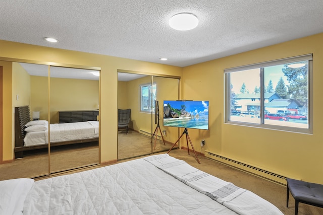 bedroom with baseboards, a baseboard heating unit, multiple closets, and carpet floors