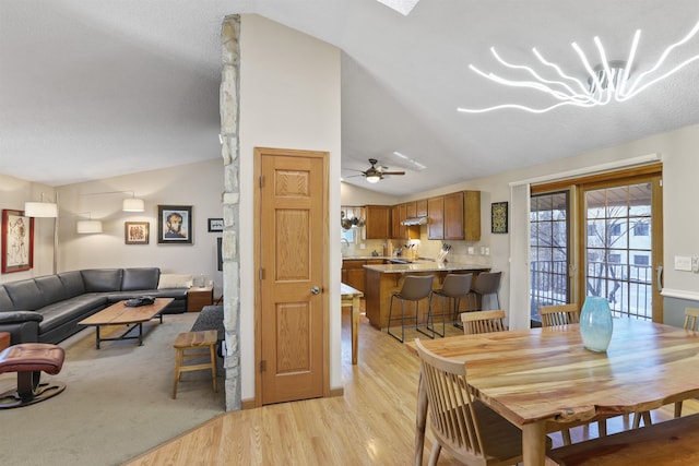 dining space with light wood-type flooring, a ceiling fan, and vaulted ceiling