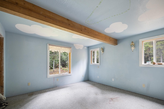 carpeted empty room with beamed ceiling and a wealth of natural light