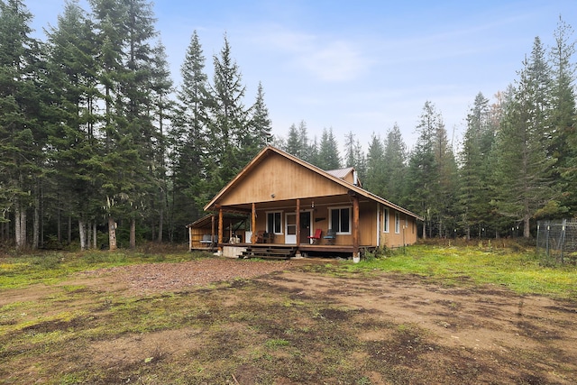 view of front of home with a porch and a forest view