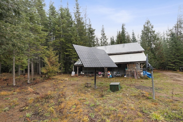 view of front of house with metal roof, a view of trees, and solar panels