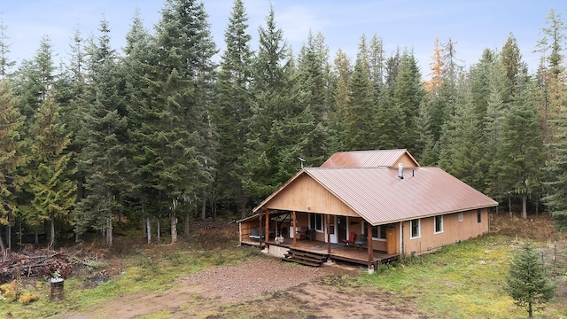 view of front facade with a forest view, a porch, and metal roof