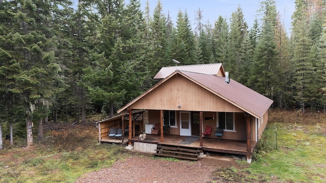 view of front of home featuring a porch, metal roof, and a view of trees