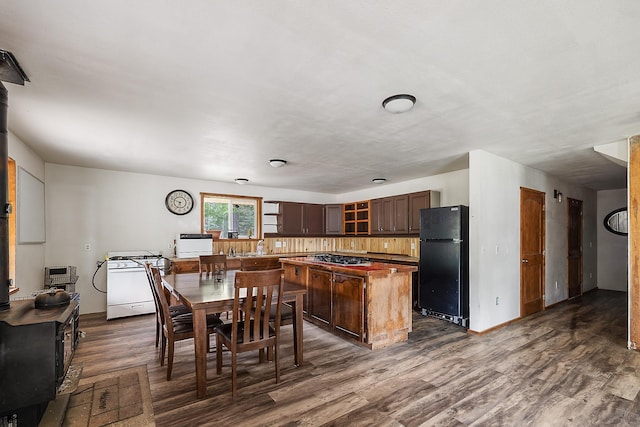 kitchen featuring a kitchen island, freestanding refrigerator, dark wood-type flooring, dark brown cabinetry, and glass insert cabinets