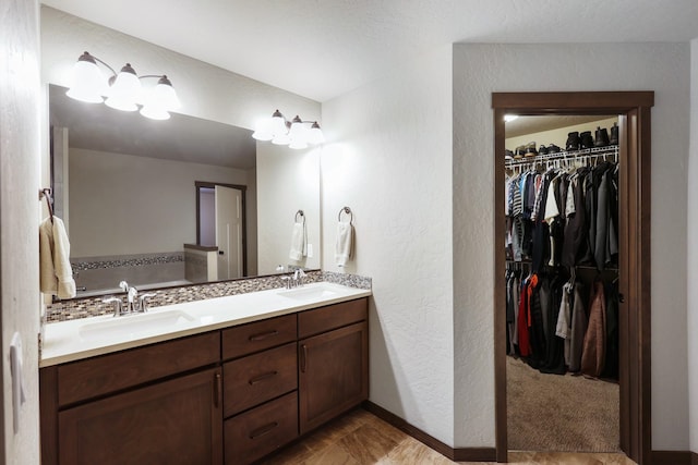 full bath with double vanity, a spacious closet, a garden tub, and a sink