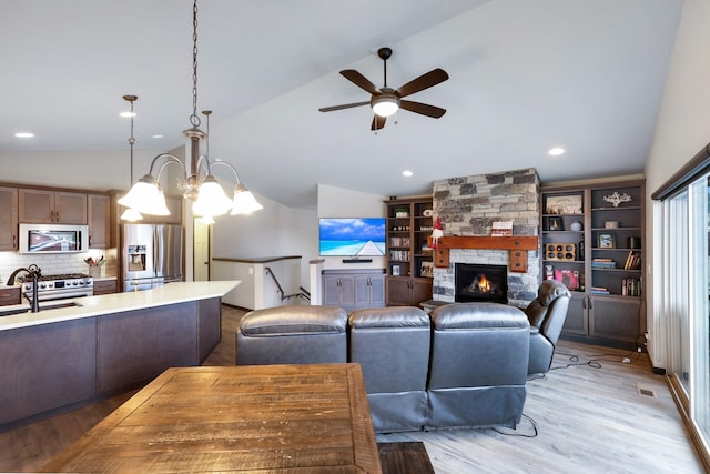 living area featuring recessed lighting, light wood-style floors, a stone fireplace, ceiling fan, and vaulted ceiling