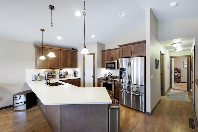 kitchen featuring visible vents, backsplash, a peninsula, stainless steel appliances, and a sink