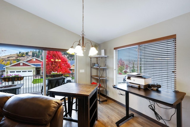 dining space featuring a chandelier, wood finished floors, baseboards, and vaulted ceiling