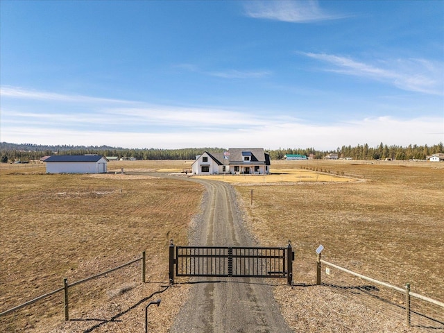 view of road featuring dirt driveway, a rural view, a gated entry, and a gate