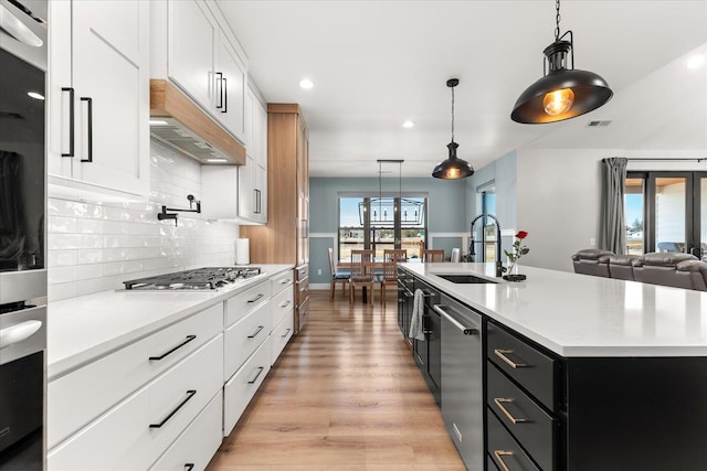 kitchen featuring tasteful backsplash, a sink, light countertops, stainless steel appliances, and dark cabinets