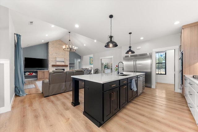 kitchen featuring light wood finished floors, appliances with stainless steel finishes, light countertops, and a sink