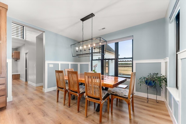 dining room featuring light wood-type flooring, baseboards, visible vents, and an inviting chandelier