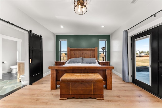 bedroom with access to exterior, baseboards, light wood-style floors, and a barn door