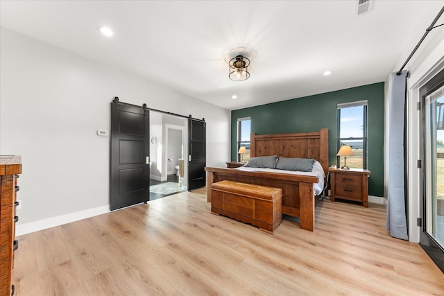 bedroom with visible vents, light wood-style flooring, recessed lighting, a barn door, and baseboards