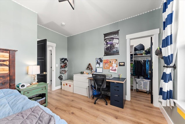 bedroom featuring a spacious closet, baseboards, a closet, and light wood finished floors