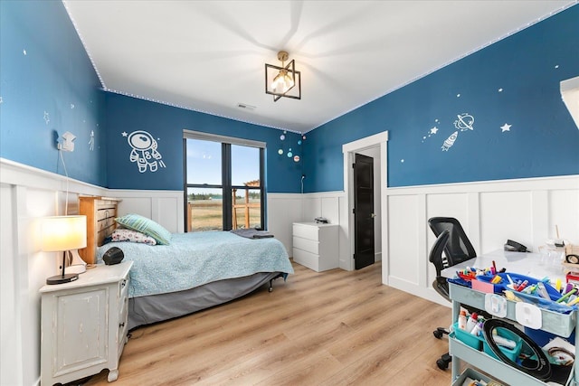 bedroom with visible vents, wood finished floors, and wainscoting