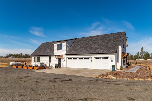 view of front of home with concrete driveway, an attached garage, and a shingled roof