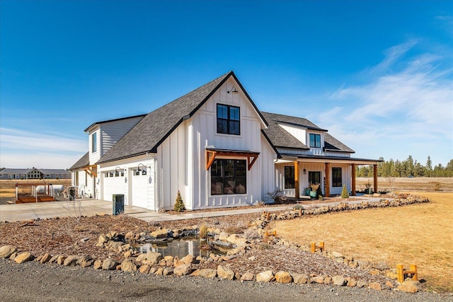 modern farmhouse with board and batten siding, concrete driveway, roof with shingles, covered porch, and an attached garage