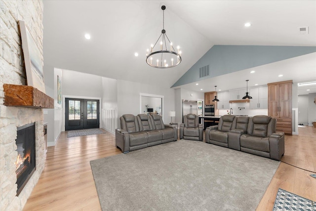 living area featuring a notable chandelier, light wood-style floors, visible vents, and high vaulted ceiling