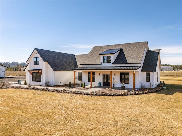 modern inspired farmhouse with board and batten siding, a front lawn, a porch, metal roof, and a standing seam roof