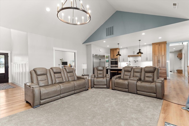 living room with visible vents, high vaulted ceiling, recessed lighting, an inviting chandelier, and light wood finished floors