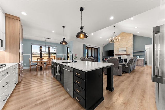 kitchen with a sink, light wood-style floors, dark cabinets, and light countertops