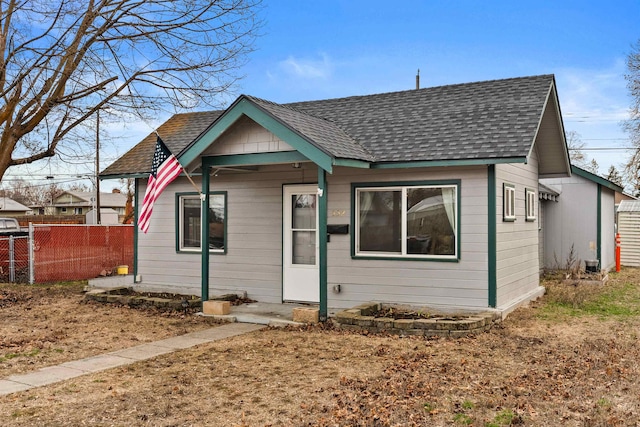 bungalow-style house with a shingled roof and fence