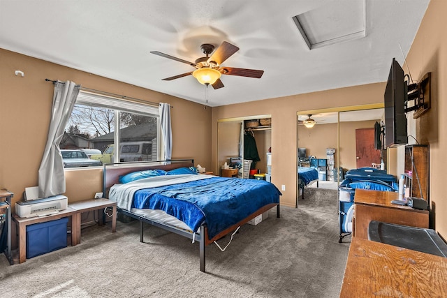 bedroom with attic access, multiple closets, carpet floors, and ceiling fan