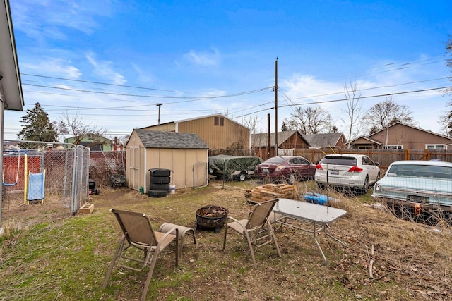 view of yard featuring an outbuilding, a shed, an outdoor fire pit, and fence