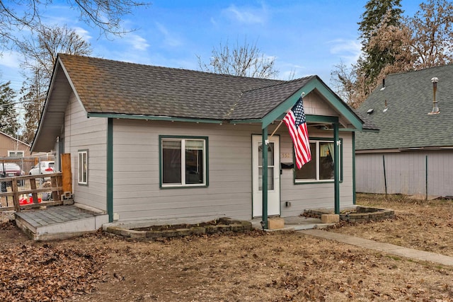 back of house featuring fence and a shingled roof