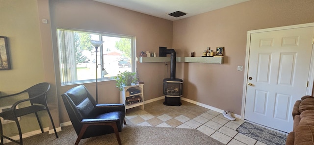 sitting room with light tile patterned floors, a wood stove, and baseboards