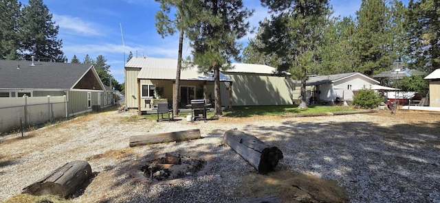 rear view of house with metal roof, an outdoor fire pit, and fence