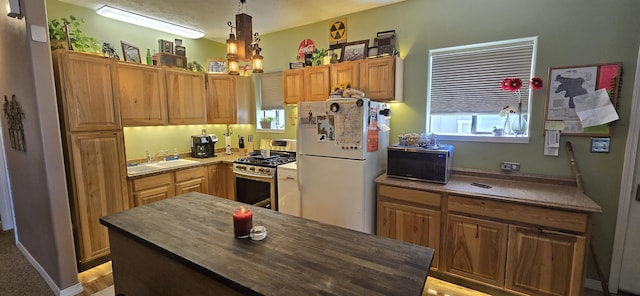 kitchen featuring gas stove, freestanding refrigerator, a sink, hanging light fixtures, and black microwave