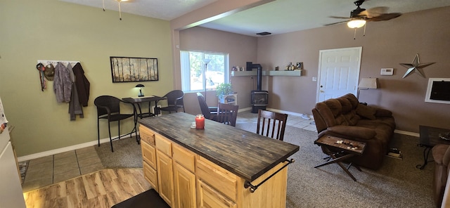 kitchen featuring open floor plan, ceiling fan, and a wood stove