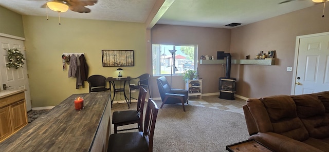 living room featuring baseboards, a wood stove, and a ceiling fan