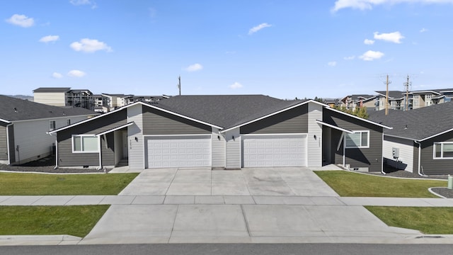 view of front of house with a shingled roof, a front lawn, concrete driveway, a garage, and a residential view