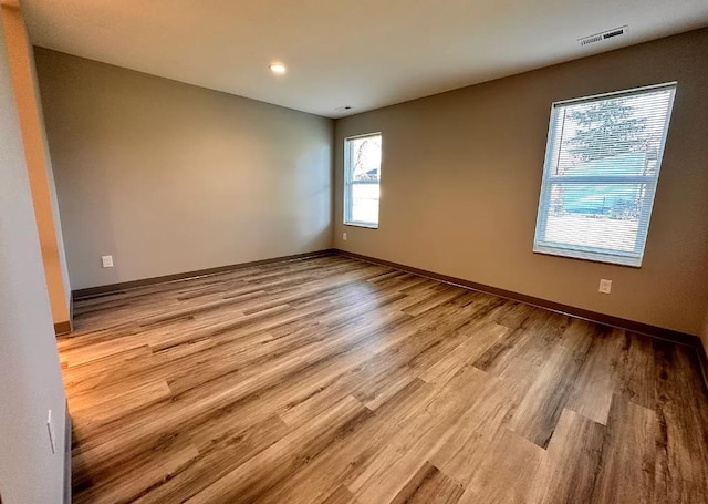 empty room featuring visible vents, light wood-style flooring, and baseboards