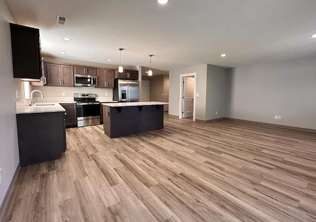 kitchen featuring visible vents, a sink, a kitchen island, stainless steel appliances, and light countertops