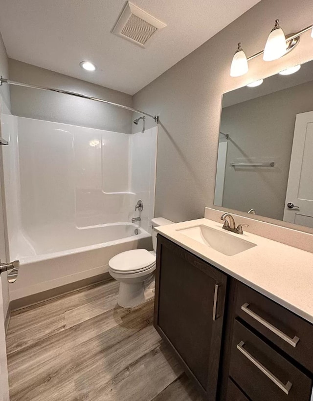 full bathroom with visible vents, toilet, wood finished floors, washtub / shower combination, and vanity