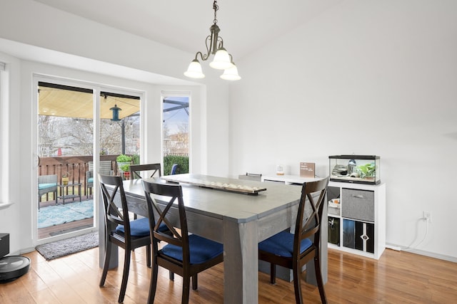 dining area with a chandelier, baseboards, and light wood-style flooring