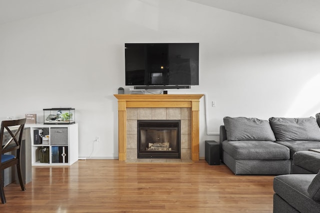 living room with lofted ceiling, wood finished floors, and a tiled fireplace