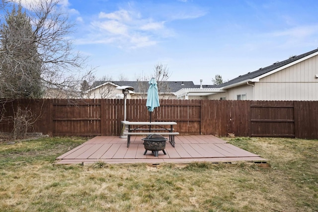 view of yard featuring a deck, a fire pit, and a fenced backyard